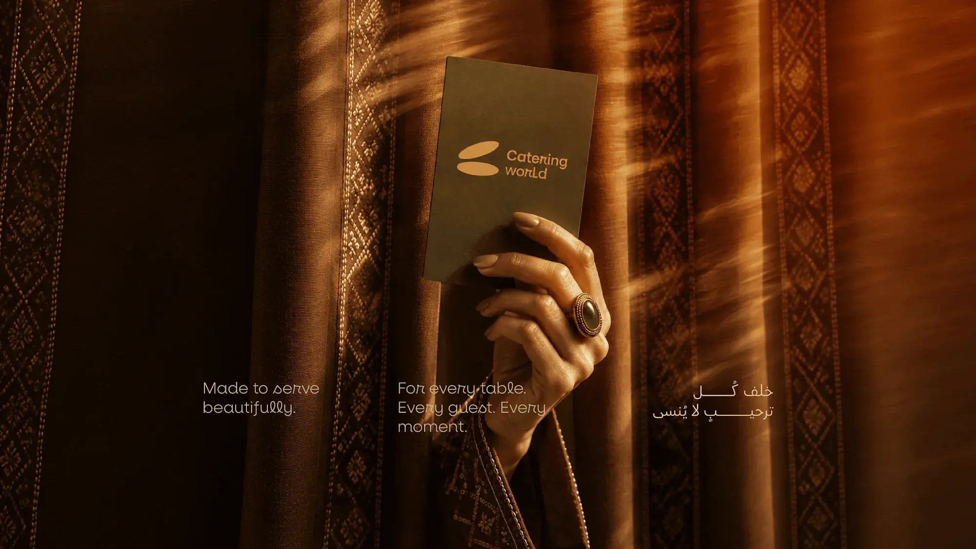 A hand holding a Catering World card against a patterned curtain